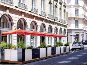 um edifício com guarda-sóis vermelhos numa rua da cidade em Mercure Lyon Centre Plaza République em Lyon