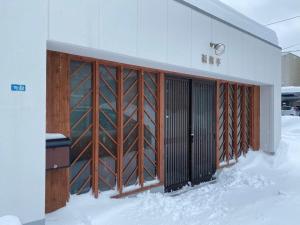 a building with wooden doors in the snow at 福偉亭 in Otaru