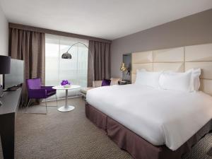a hotel room with a large white bed and a desk at Sofitel Warsaw Victoria in Warsaw +180 photos