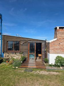 a house with a wooden deck with a green chair at La Farola del Cabo in Cabo Polonio