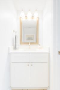 een witte badkamer met een wastafel en een spiegel bij Beachside Bliss - Neptune Nook Unit 1 in Jacksonville Beach