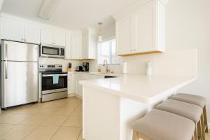 een witte keuken met witte apparaten en witte kasten bij Beachside Bliss - Neptune Nook Unit 1 in Jacksonville Beach