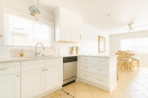 een witte keuken met witte kasten en een tafel bij Beachside Bliss - Neptune Nook Unit 1 in Jacksonville Beach +6 foto's
