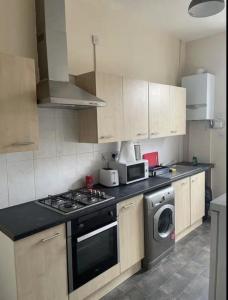 a kitchen with a stove and a washing machine at Lubona Stirchley Guest House in Birmingham