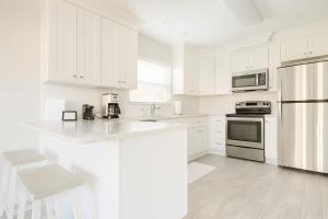 a white kitchen with white cabinets and a counter top at Beachside Bliss - Neptune Nook Unit 2 in Jacksonville Beach