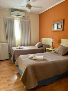 duas camas em um quarto com paredes laranja em HOTEL LOS TILOS RECONQUISTA em Reconquista