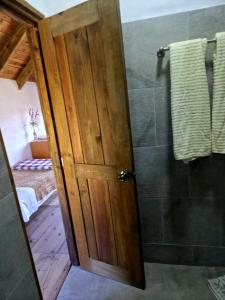 a bathroom with a shower with a wooden door at Cabañas Las orquídeas in Huasca de Ocampo