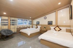 um quarto com duas camas e uma cadeira em NGỌC BẢO CHÂU HOTEL em Da Lat