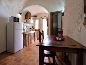 a kitchen with a wooden table and a white refrigerator at Cave House in Guadix with Private Pool in Bejarín