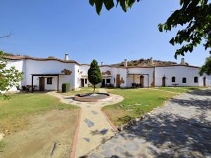 a large white house with a tree in the yard at Cave House in Guadix with Private Pool in Bejarín