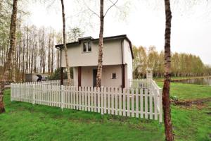 a small house behind a white picket fence at Holiday Home near Ko obrzeg with Private Pond in Nieżyn