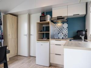 Una cocina con gabinetes blancos y un microondas. en Chalet in Nature, Friesland, en De Veenhoop