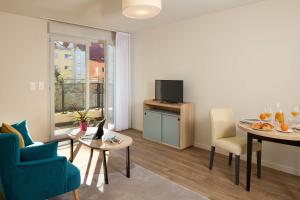 a living room with a table and chairs and a television at Quality Suites Nancy Centre in Nancy