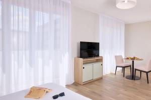 Una sala de estar con un televisor y una mesa con una silla. en Quality Suites Reims - Saint-Thomas, en Reims