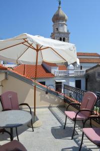 eine Terrasse mit Stühlen, einem Sonnenschirm und einem Gebäude in der Unterkunft Apartments Hedviga in Krk