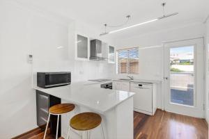 Surf's Up Sawtell في ساوتيل: مطبخ أبيض مع كونتر وشرفتين