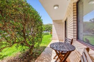 Surf's Up Sawtell في ساوتيل: طاولة ومقعد على شرفة مع نافذة