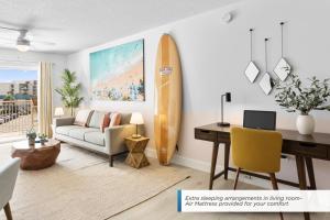 a living room with a desk and a surfboard at Cocoa Beach Towers - Oceanfront Resort with Heated Pool, Tennis Steps from the Pier in Cocoa Beach