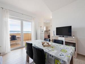 ein Esszimmer mit einem Tisch mit Stühlen und einem Fernseher in der Unterkunft Apartment in Nevidane near White Mountains in Neviđane