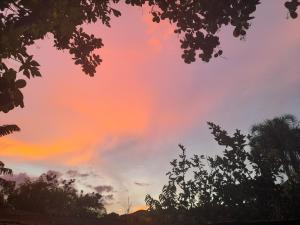 un tramonto nel cielo con alberi in primo piano di Cantinho Descanvida Temporada a Água Boa