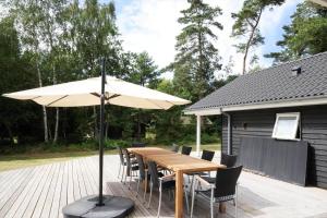 una mesa de madera y sillas con una sombrilla en la terraza en 10069-Rorvig-Harestykket-3, en Rørvig
