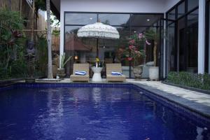 een zwembad met stoelen en een parasol naast een huis bij Villa La Familia Dua in Canggu