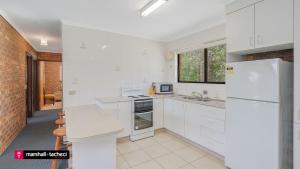 a kitchen with white appliances and a brick wall at Cuttagee Beach Cottage 3 - Tathra Bermagui Rd 3521 in Barragga Bay