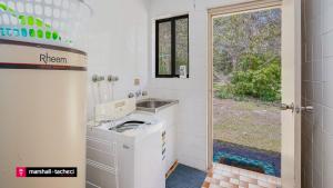 a washing machine in a bathroom with a window at Cuttagee Beach Cottage 3 - Tathra Bermagui Rd 3521 in Barragga Bay