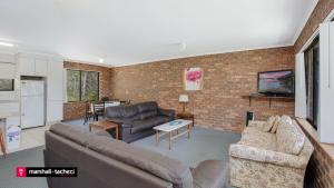 a living room with two couches and a kitchen at Cuttagee Beach Cottage 3 - Tathra Bermagui Rd 3521 in Barragga Bay