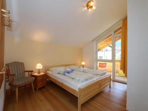 Un dormitorio con una cama, una silla y una ventana en Apartment in Zugspitz Arena near Hiking Trails, en Bichlbach