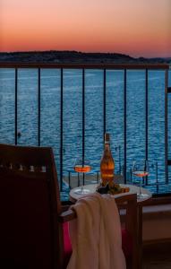 
a bottle of wine sitting on a balcony overlooking a body of water at Bacacan Otel in Ayvalık
