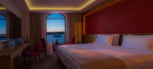 
a hotel room with a large bed and a large window at Bacacan Otel in Ayvalık
