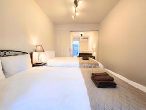 a hotel room with two beds with towels on the floor at 新大阪ゲストハウス 新大阪駅徒歩5分のリノベーション貸切宿 in Osaka