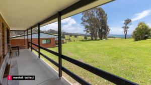 a balcony with a view of a field of grass at Cuttagee Beach Cottage 5 in Barragga Bay