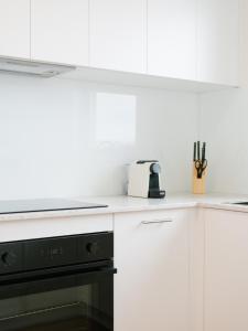 una cocina con armarios blancos y horno negro en Prickly Pear Stays in Merewether - Ranclaud St, en Merewether