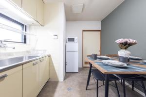 a kitchen with a table with chairs and a refrigerator at HITOYADO kanazawa in Kanazawa