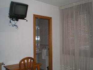 a room with a television and a table and a window at Hostal Maurin in Vilaller