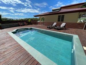 una piscina en una terraza con 2 sillas y una casa en Parahimai Lodge, en Farehau
