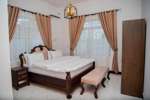 una camera da letto con un letto, una sedia e finestre di BNJ Royal Palace a Dar es Salaam Altre 9 foto