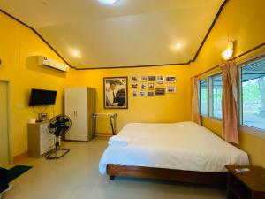 a bedroom with a bed and a yellow wall at บ้านกลางสวนผึ้ง in Ratchaburi