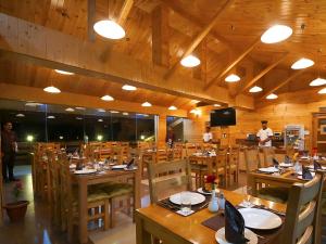 um restaurante com mesas e cadeiras de madeira e uma TV em Vivaan The Sunrise em Manali