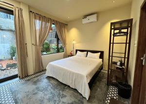 a bedroom with a white bed and a large window at Nhà thơ Homestay in Cồn Giả Viên