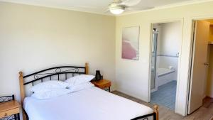 a bedroom with a bed and a bathroom with a tub at Tanjil Cottage in Lakes Entrance