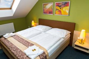 ein Schlafzimmer mit einem Bett in einem grünen Zimmer in der Unterkunft Hotel Rieger Garni in Jičín