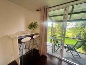 a room with a table and chairs and a balcony at Domeczech Off-Grid Charm in Dargaville