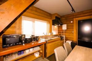 Una cocina con fregadero y una encimera con sillas. en The LODGE ABASHIRI, en Abashiri