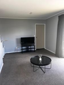 ein Wohnzimmer mit Tisch und Fernseher in der Unterkunft Lime Street Retreat in Invercargill