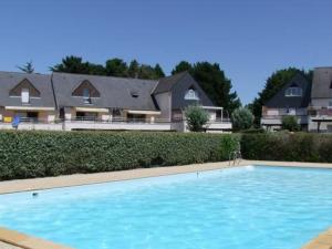 a large blue swimming pool in front of some houses at Appartement rez-de-jardin proche Port Crouesty, 4 pers, tennis, piscine, wifi - FR-1-775-50 in Arzon