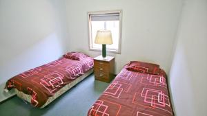 una camera con due letti, una lampada e una finestra di Fisherman's Cabin - 11 Mill Street Affordable, fishing friendly a Bermagui Altre 2 foto