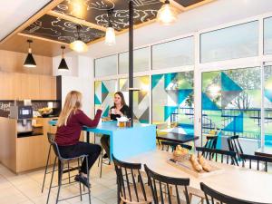 two women sitting at a table in a restaurant at Aparthotel Adagio Access Paris Vanves - Porte de Versailles in Vanves